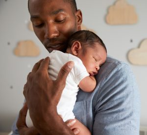 african american dad holding his new born baby in a nursery